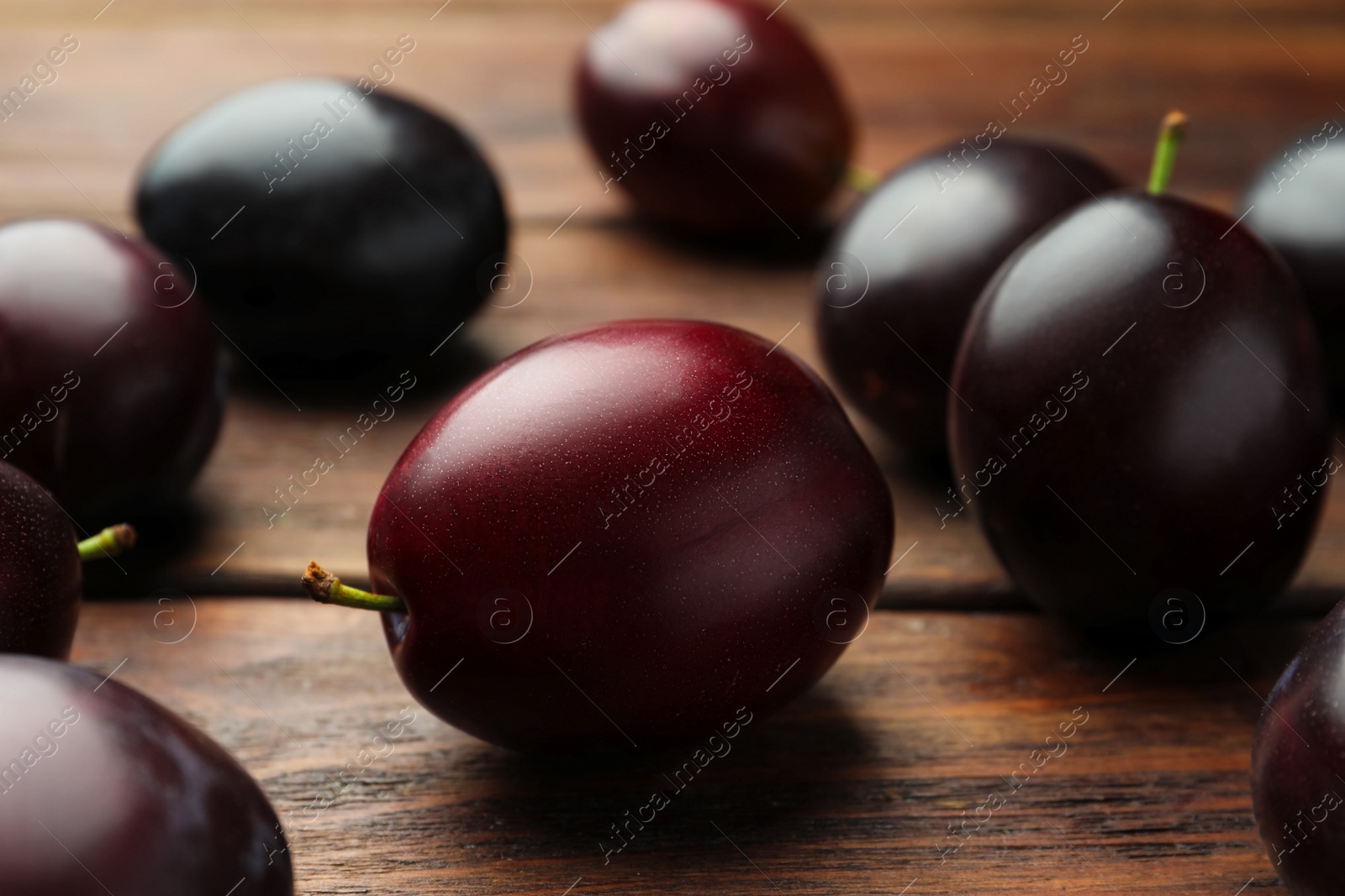 Photo of Tasty ripe plums on wooden table, closeup