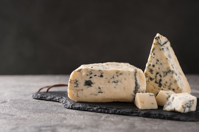 Slate board with delicious blue cheese on stone surface. Space for text