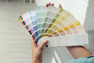 Photo of Female interior designer with color palette samples indoors, closeup