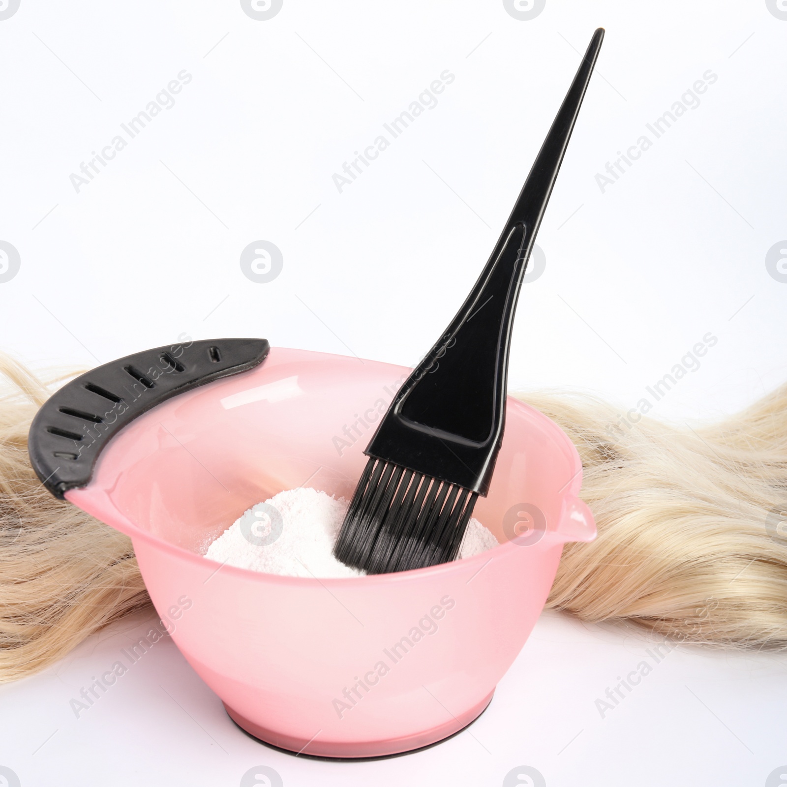 Photo of Strand of blond hair, bowl with dye and brush on white background