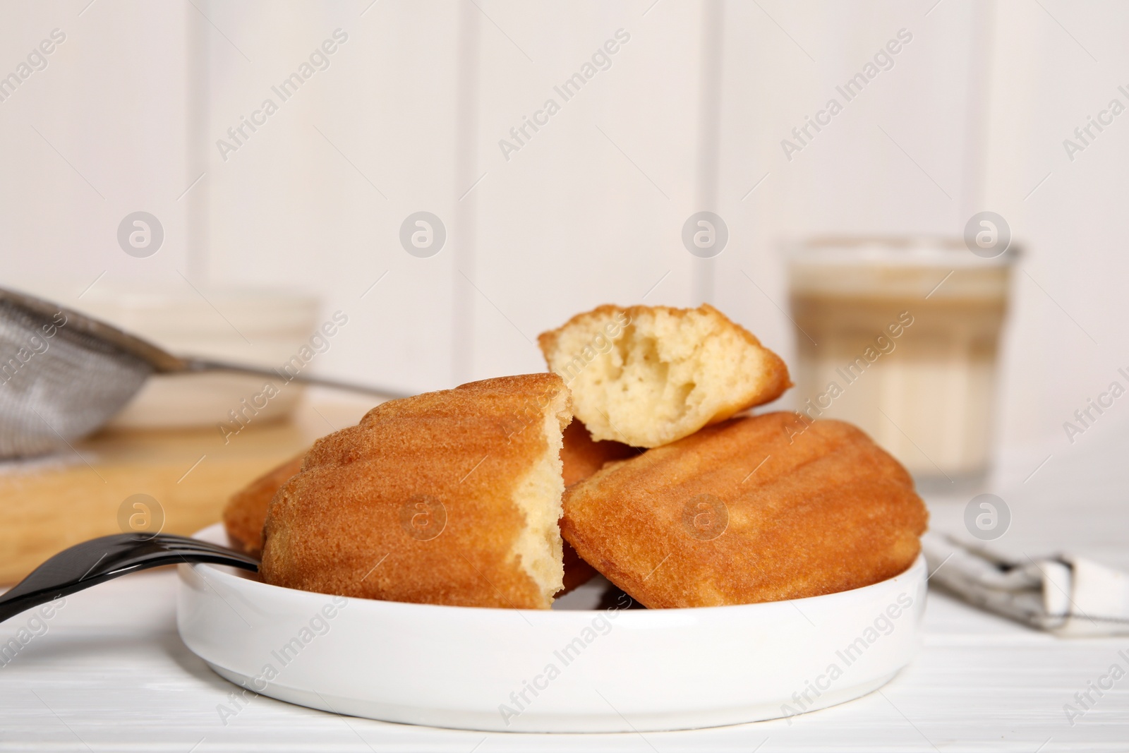 Photo of Delicious madeleine cakes on white wooden table, closeup