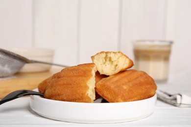 Delicious madeleine cakes on white wooden table, closeup