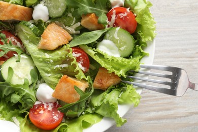 Eating delicious salad with chicken and vegetables at table, top view