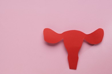 Woman`s health. Paper uterus on pale pink background, top view with space for text