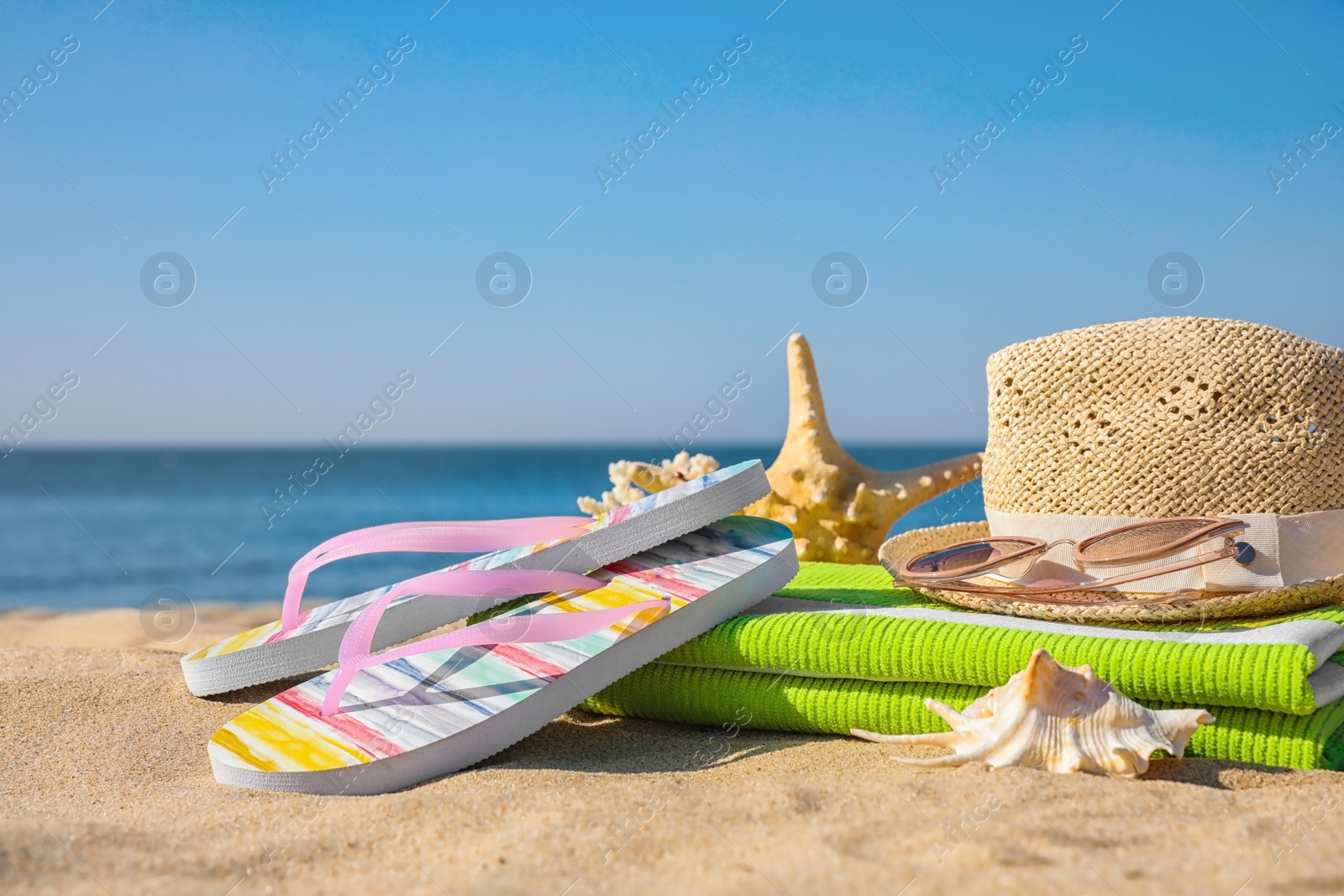 Photo of Set with stylish beach accessories on sand near sea