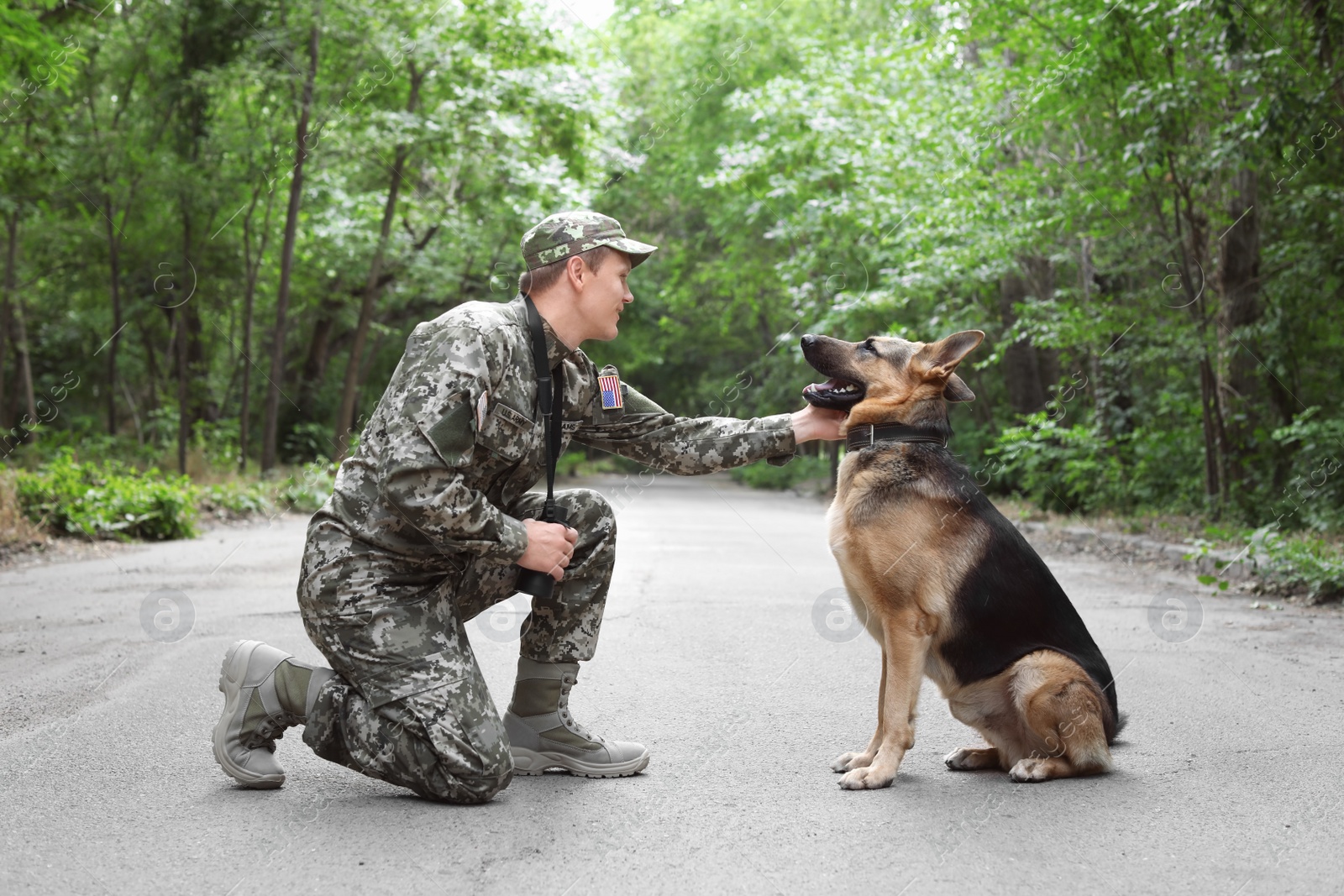 Photo of Man in military uniform with German shepherd dog, outdoors