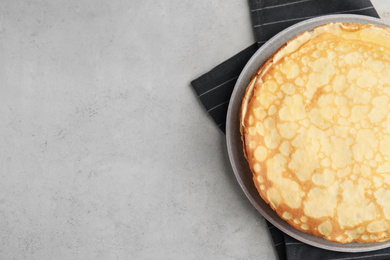 Stack of fresh thin pancakes on light grey table, top view. Space for text