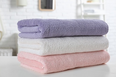 Stack of fresh towels on table in bathroom, closeup