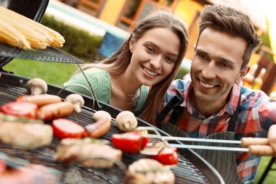 Photo of Young man and woman near barbecue grill outdoors