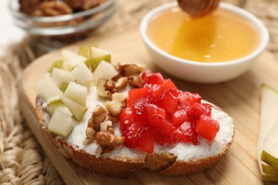 Photo of Delicious ricotta bruschetta with pear, strawberry and walnut on wooden table, closeup