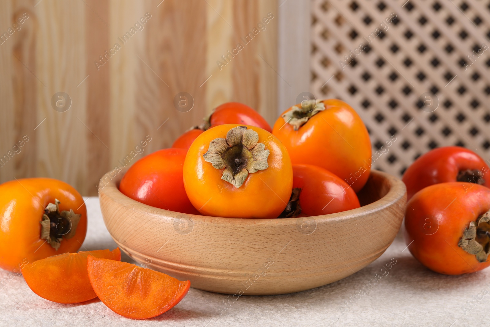 Photo of Delicious ripe persimmons on light textured table indoors, closeup