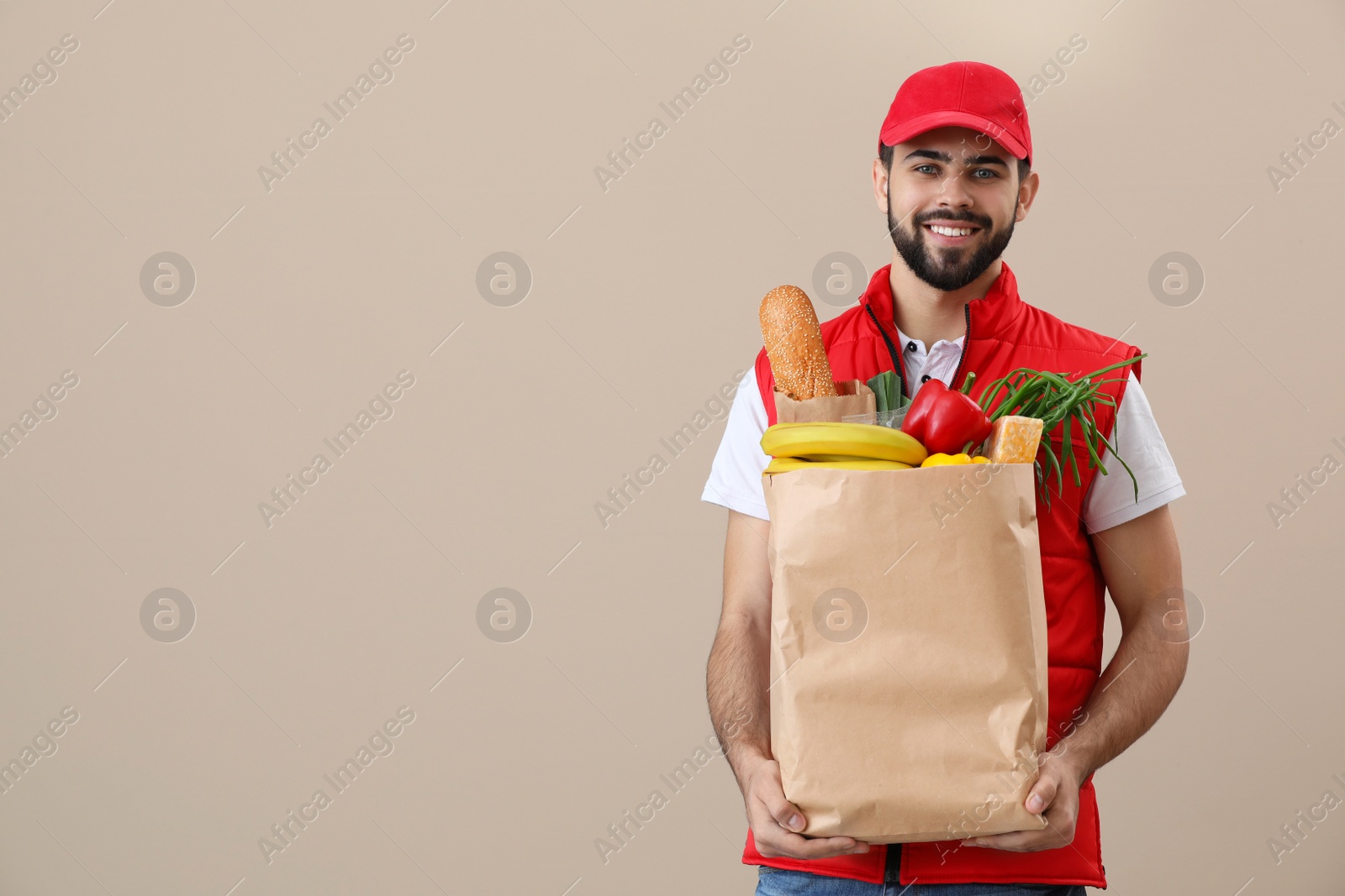 Photo of Man holding paper bag with fresh products on color background, space for text. Food delivery service