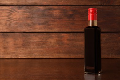 Bottle of soy sauce on wooden table. Space for text