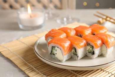 Photo of Tasty sushi rolls on grey table against blurred lights, closeup. Space for text