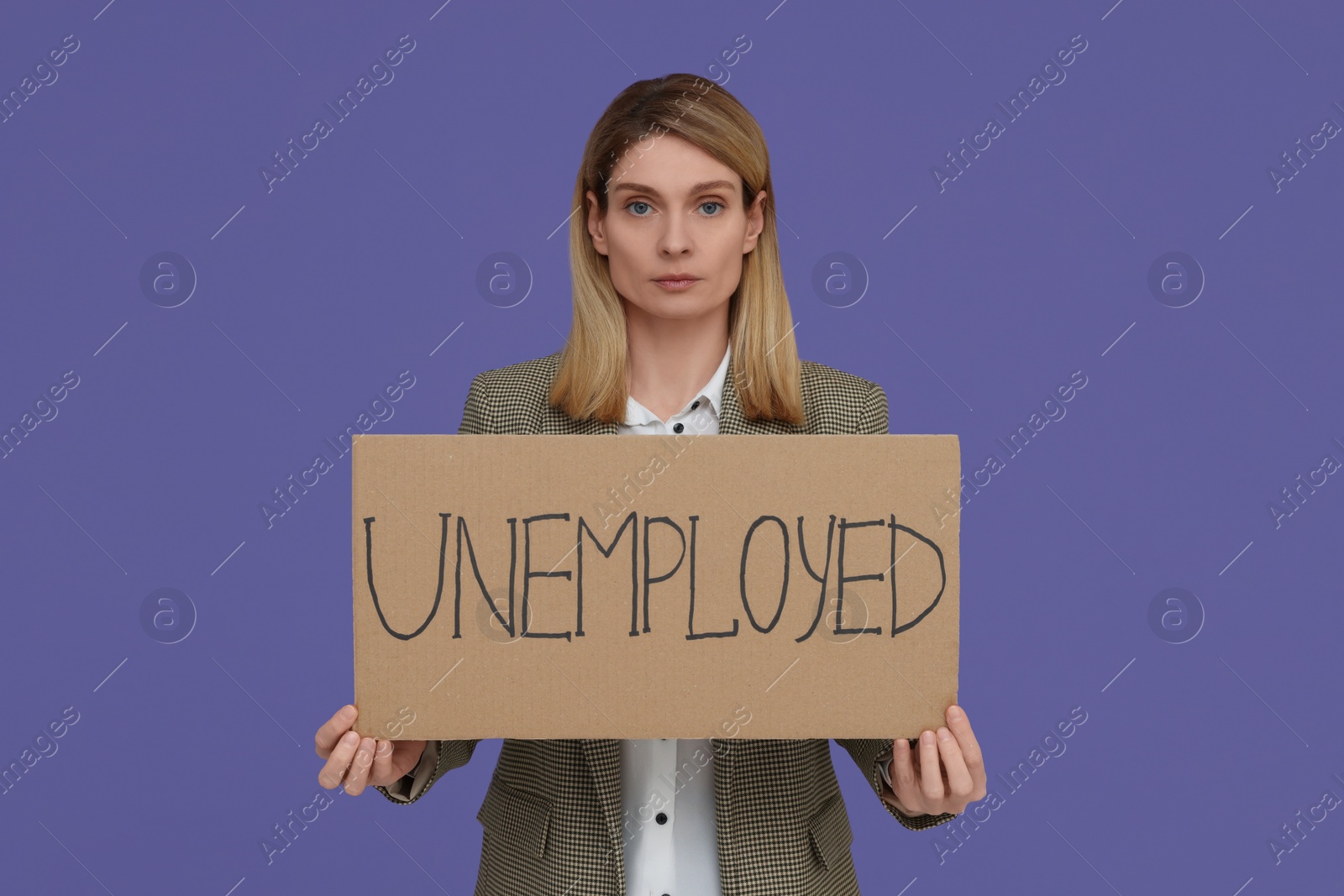 Photo of Woman holding sign with word Unemployed on violet background