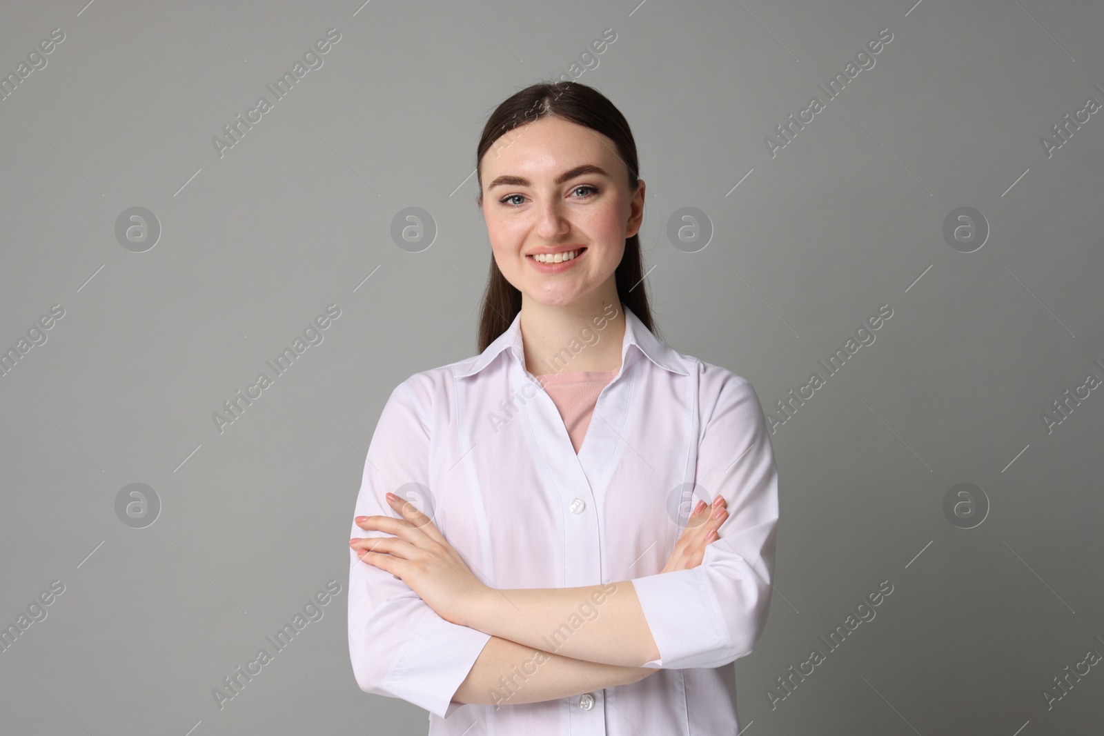 Photo of Cosmetologist in medical uniform on grey background