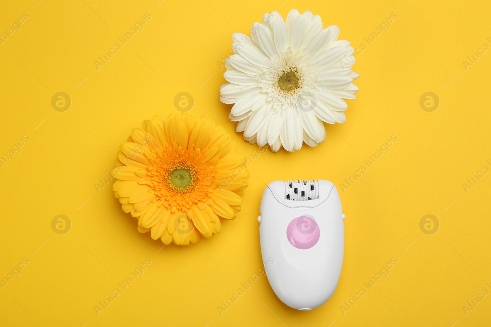 Image of Modern epilator and flowers on yellow background, flat lay 