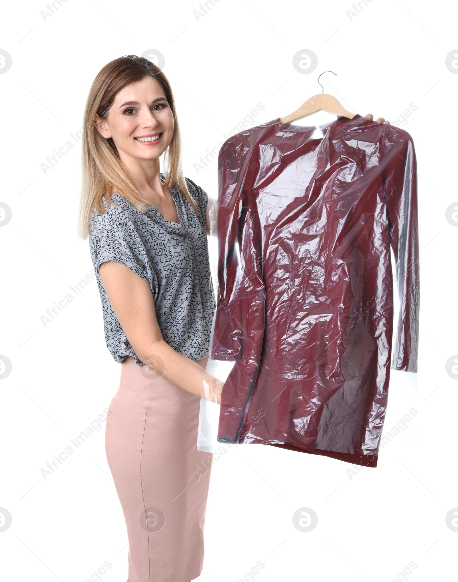 Photo of Young woman holding hanger with dress in plastic bag on white background. Dry-cleaning service