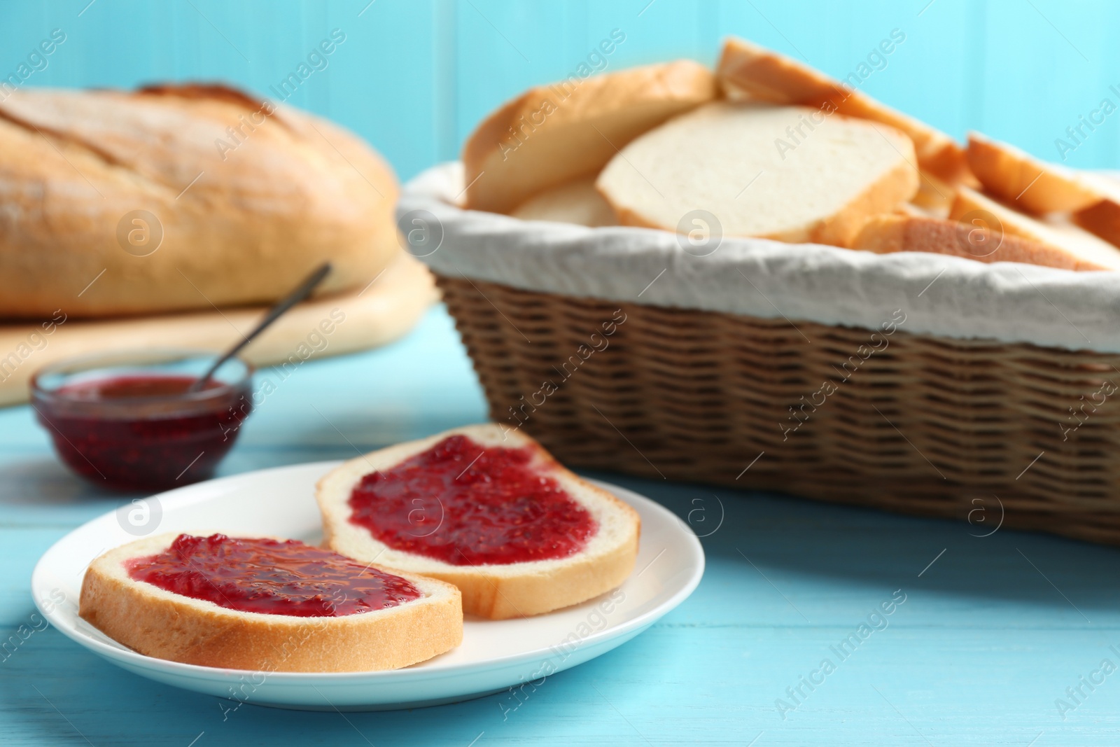 Photo of Tasty fresh bread with jam on light blue wooden table