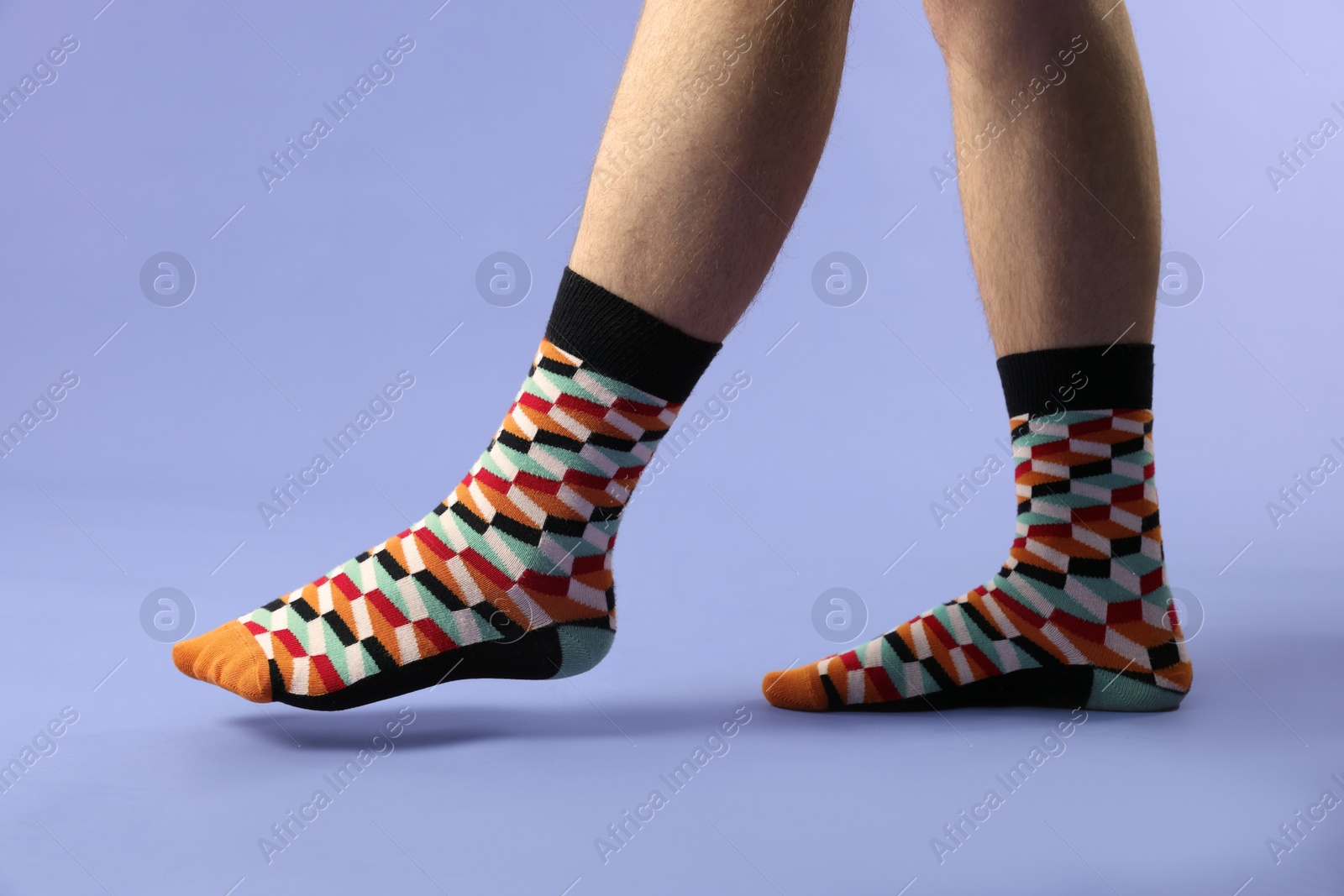 Photo of Man in stylish colorful socks on violet background, closeup