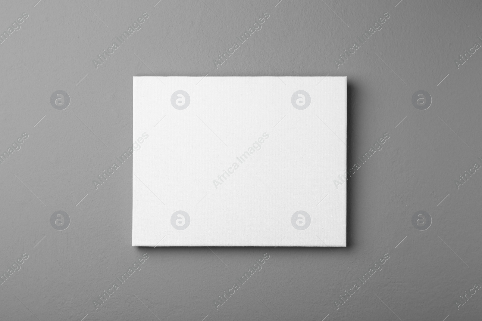 Photo of Blank canvas on grey wall. Space for design