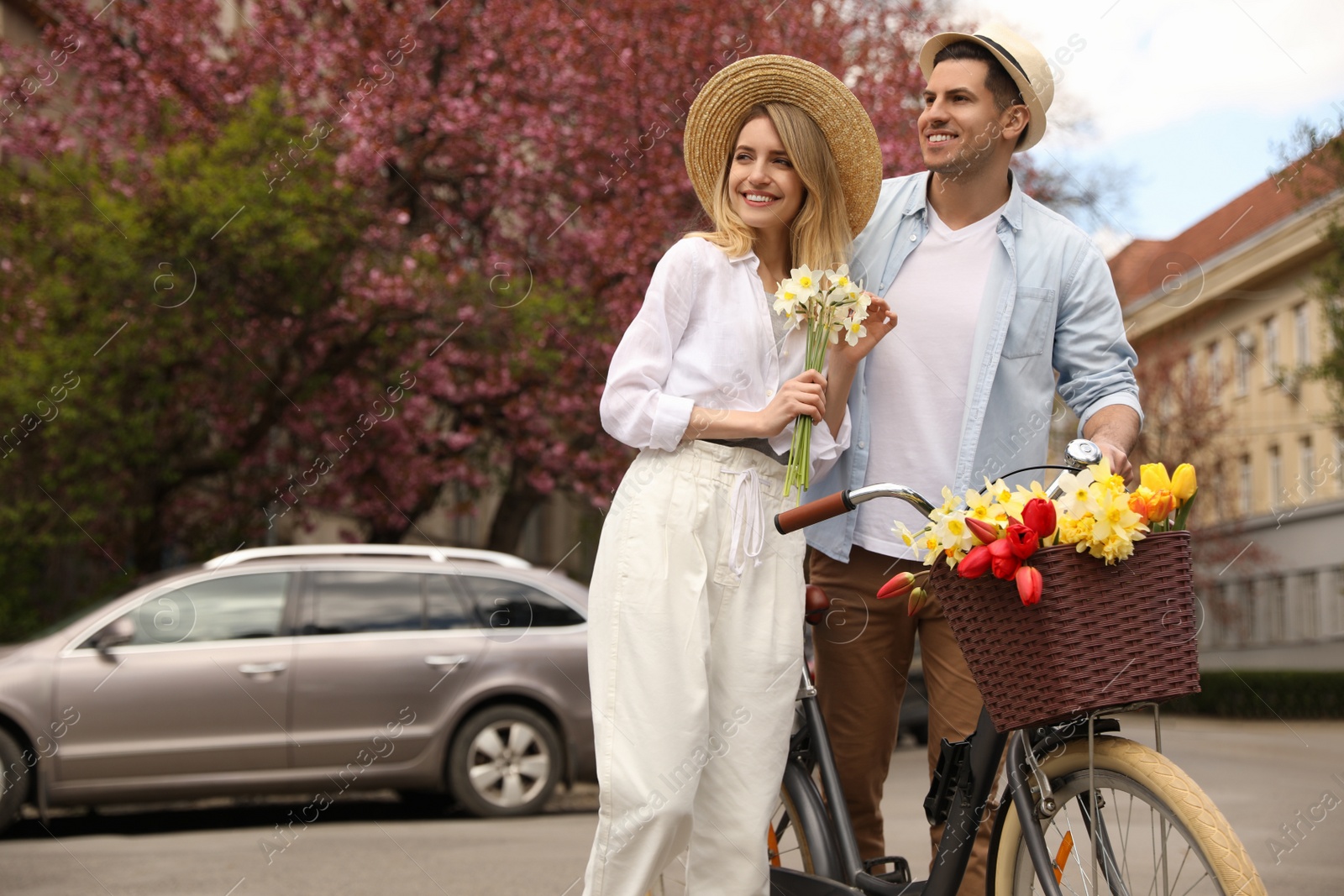 Photo of Lovely couple with bicycle and flowers on city street. Space for text