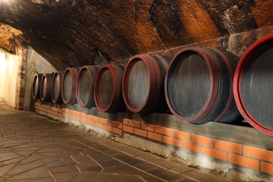 Photo of Many barrels of wine stored on shelf in cellar