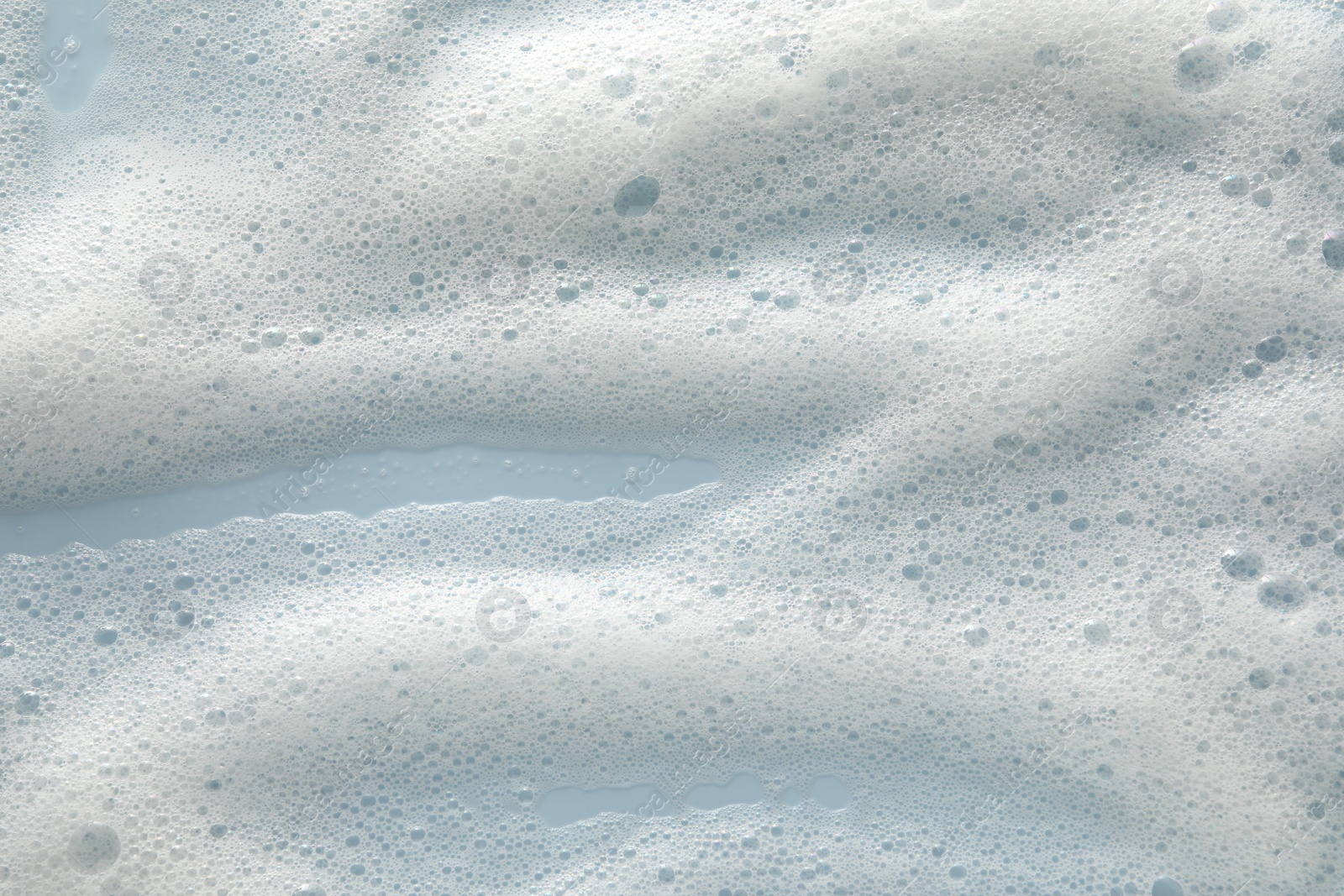 Photo of White washing foam on color background, top view