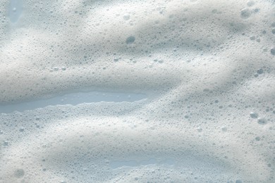 Photo of White washing foam on color background, top view