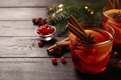 Photo of Delicious punch drink with cranberries and orange on wooden table. Space for text