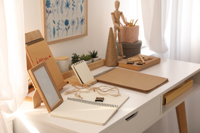 Photo of Wooden human figure and stationery on white table indoors. Interior elements