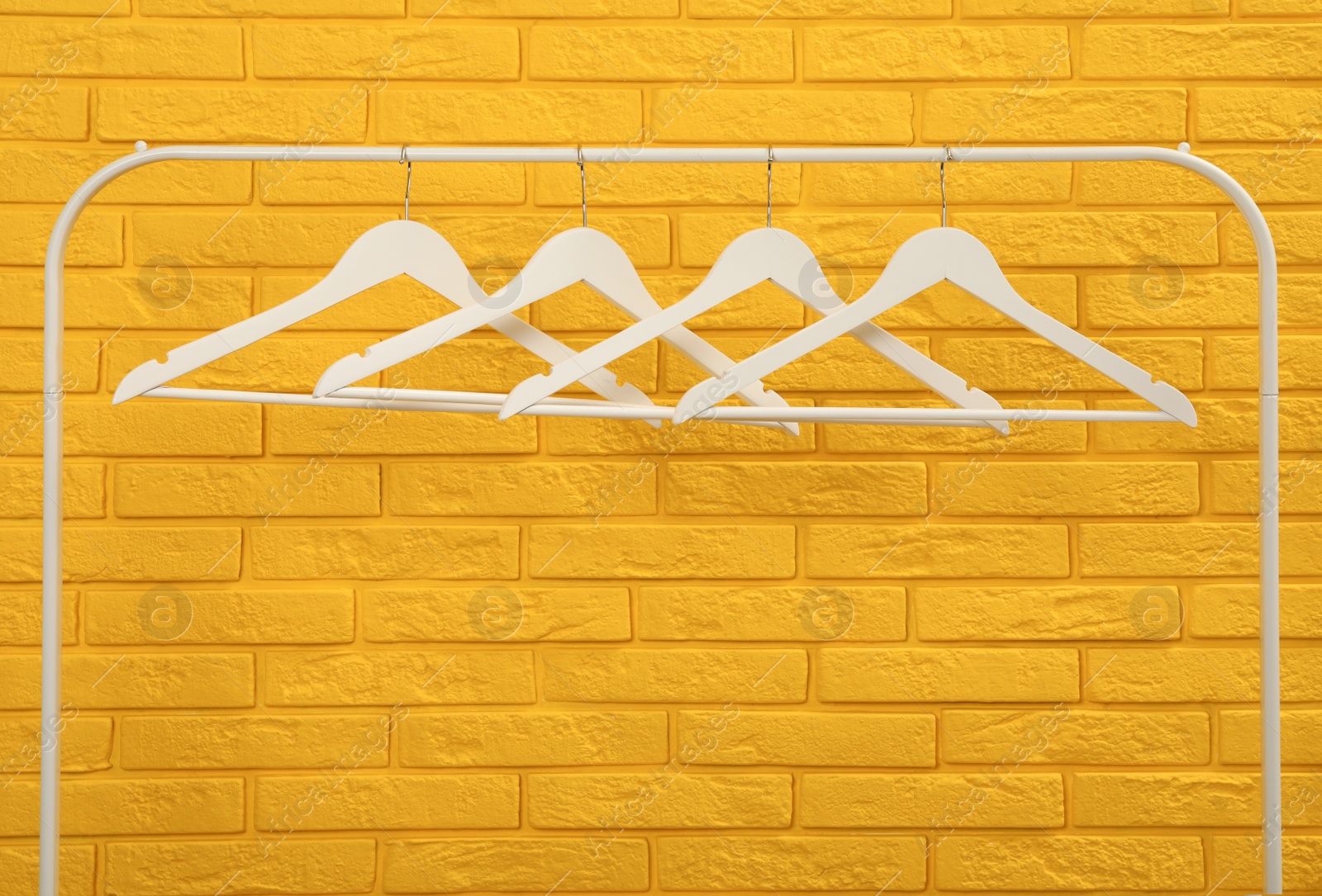 Photo of Wardrobe rack with many hangers near yellow brick wall