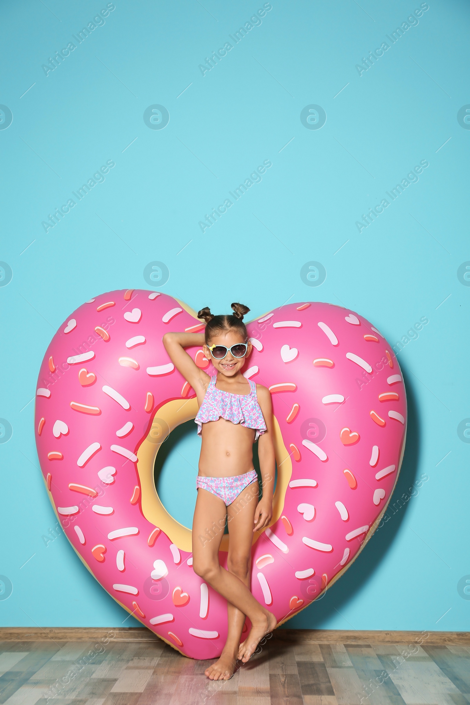 Photo of Cute little girl with inflatable heart near color wall