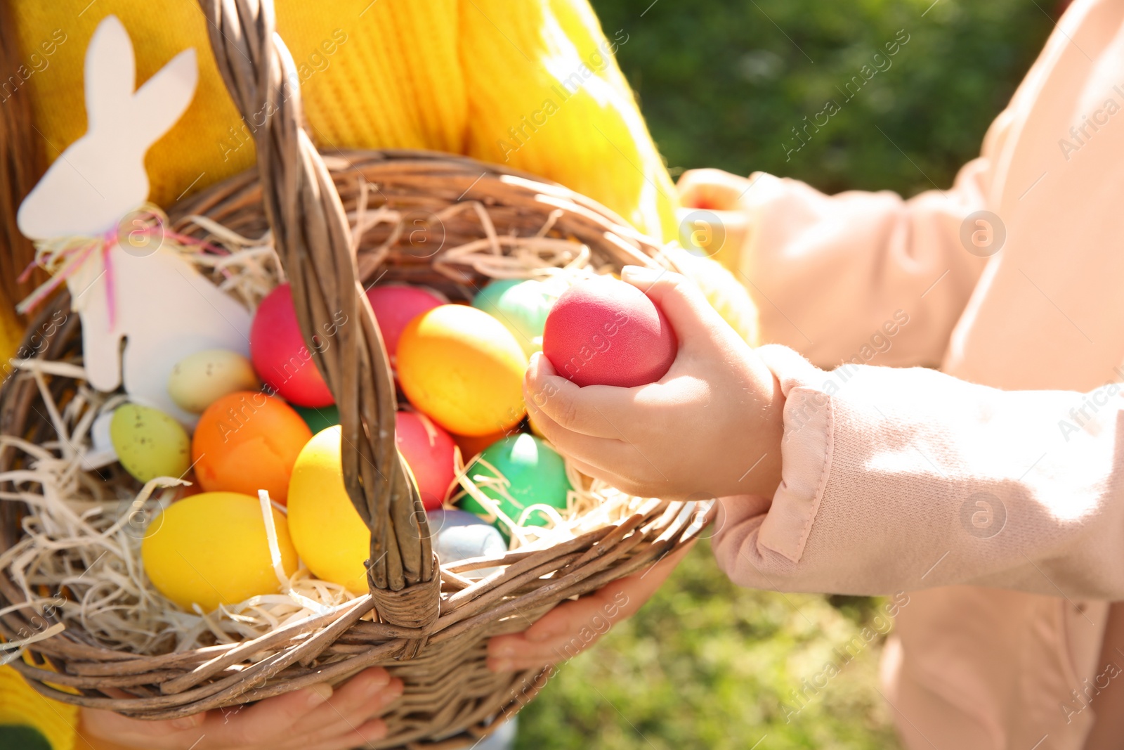 Photo of Little children with basket of Easter eggs outdoors, closeup