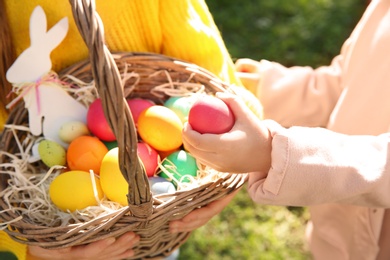 Photo of Little children with basket of Easter eggs outdoors, closeup