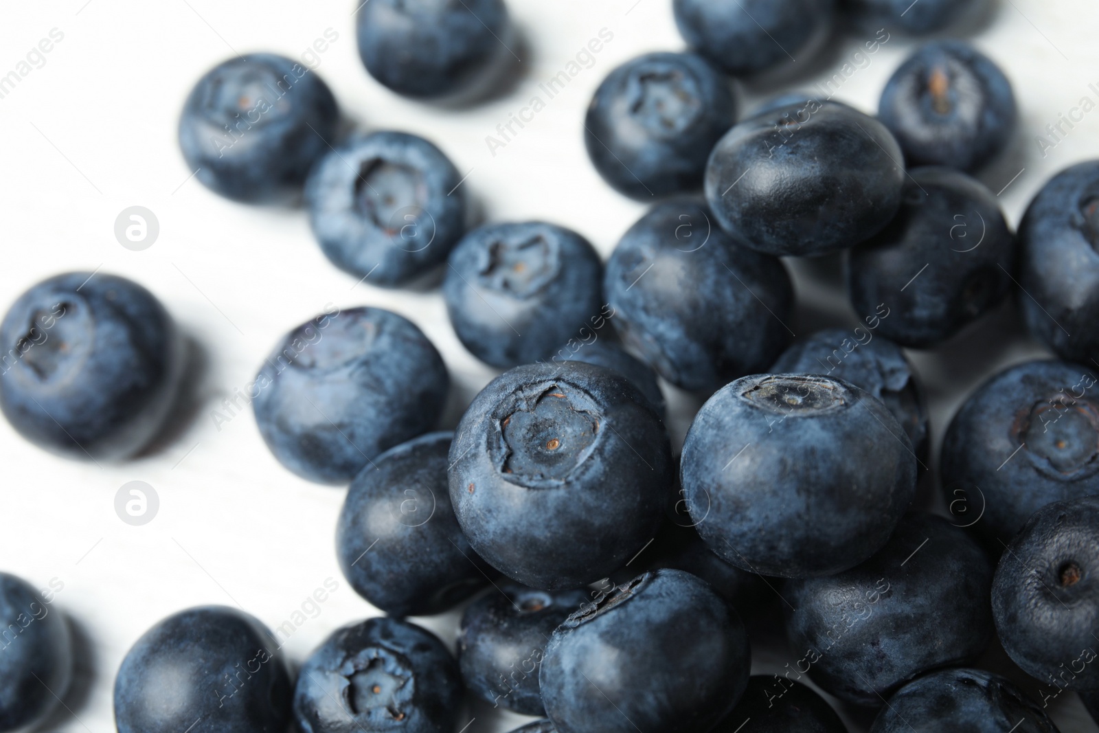 Photo of Pile of tasty fresh blueberries on white table, closeup