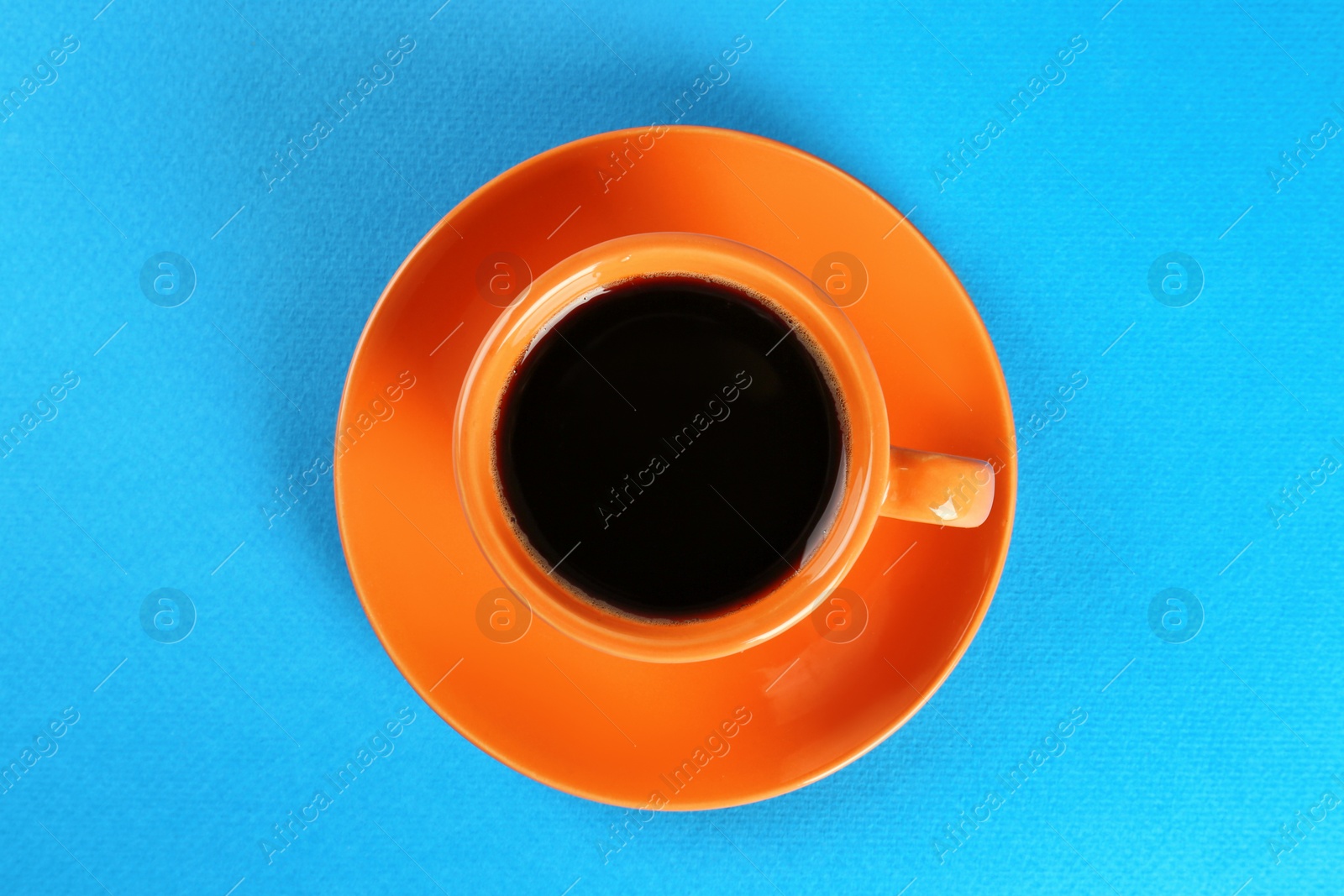 Photo of Coffee in cup on light blue background, top view