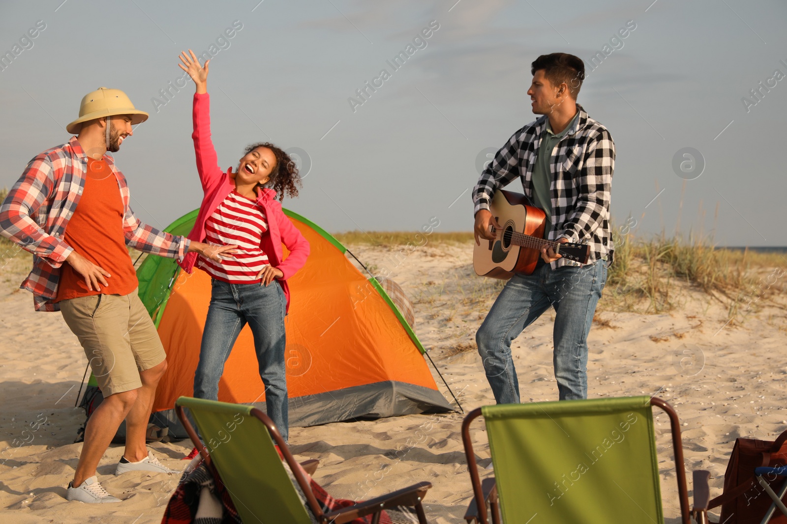 Photo of Friends having party near camping tent on sandy beach