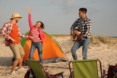 Photo of Friends having party near camping tent on sandy beach