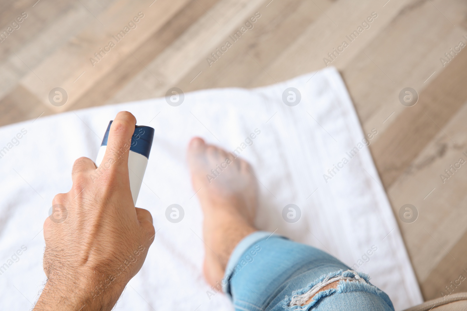 Photo of Young man using deodorant for feet at home, closeup