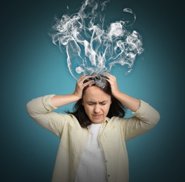Mature woman having headache on blue background. Illustration of smoke representing severe pain
