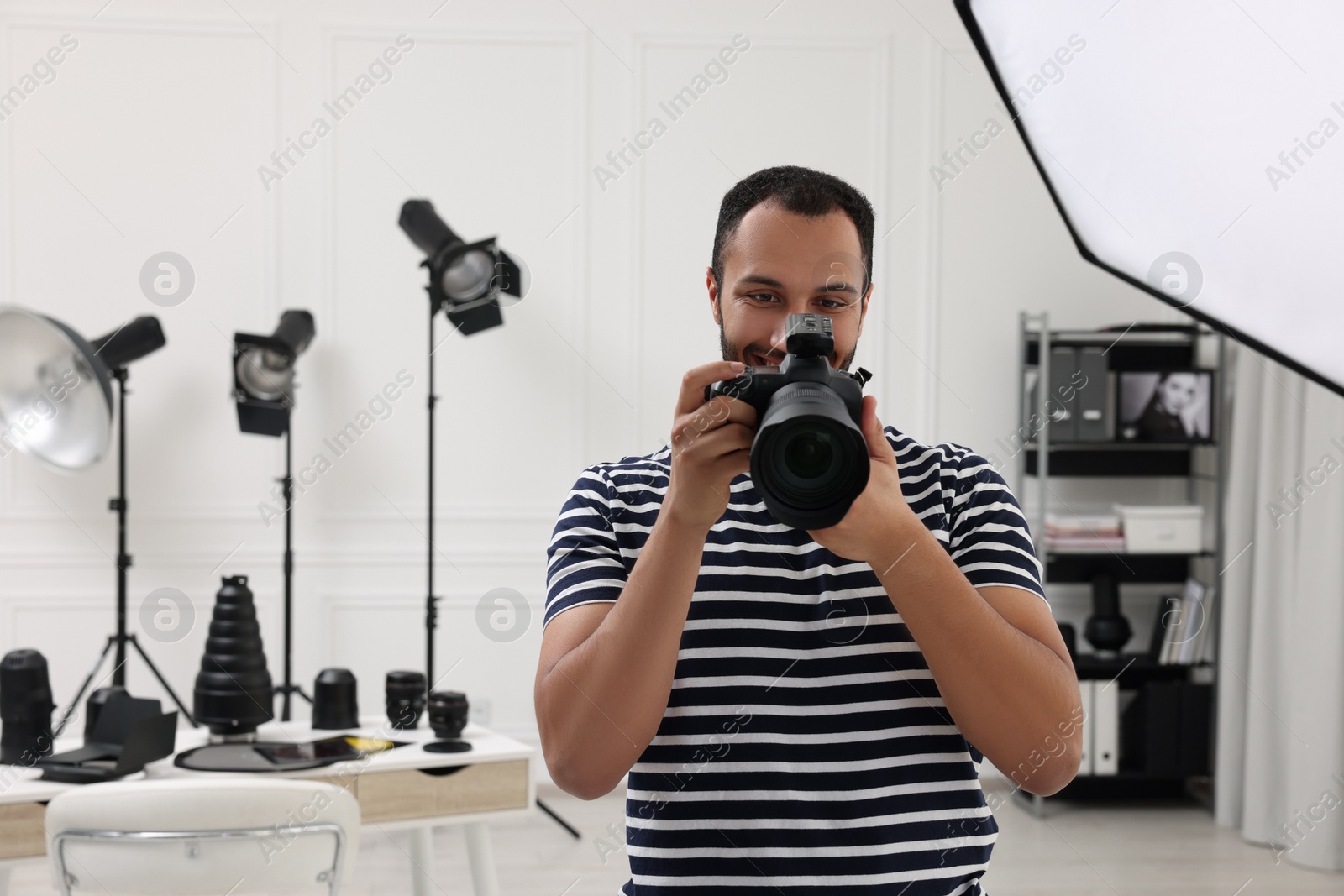 Photo of Young professional photographer with camera in modern photo studio, space for text