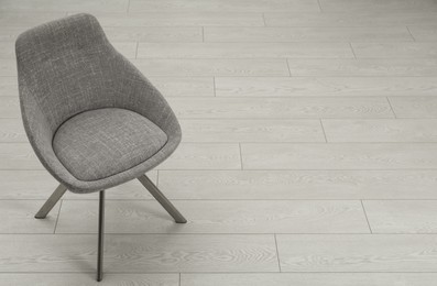Photo of Stylish grey chair on floor. Space for text