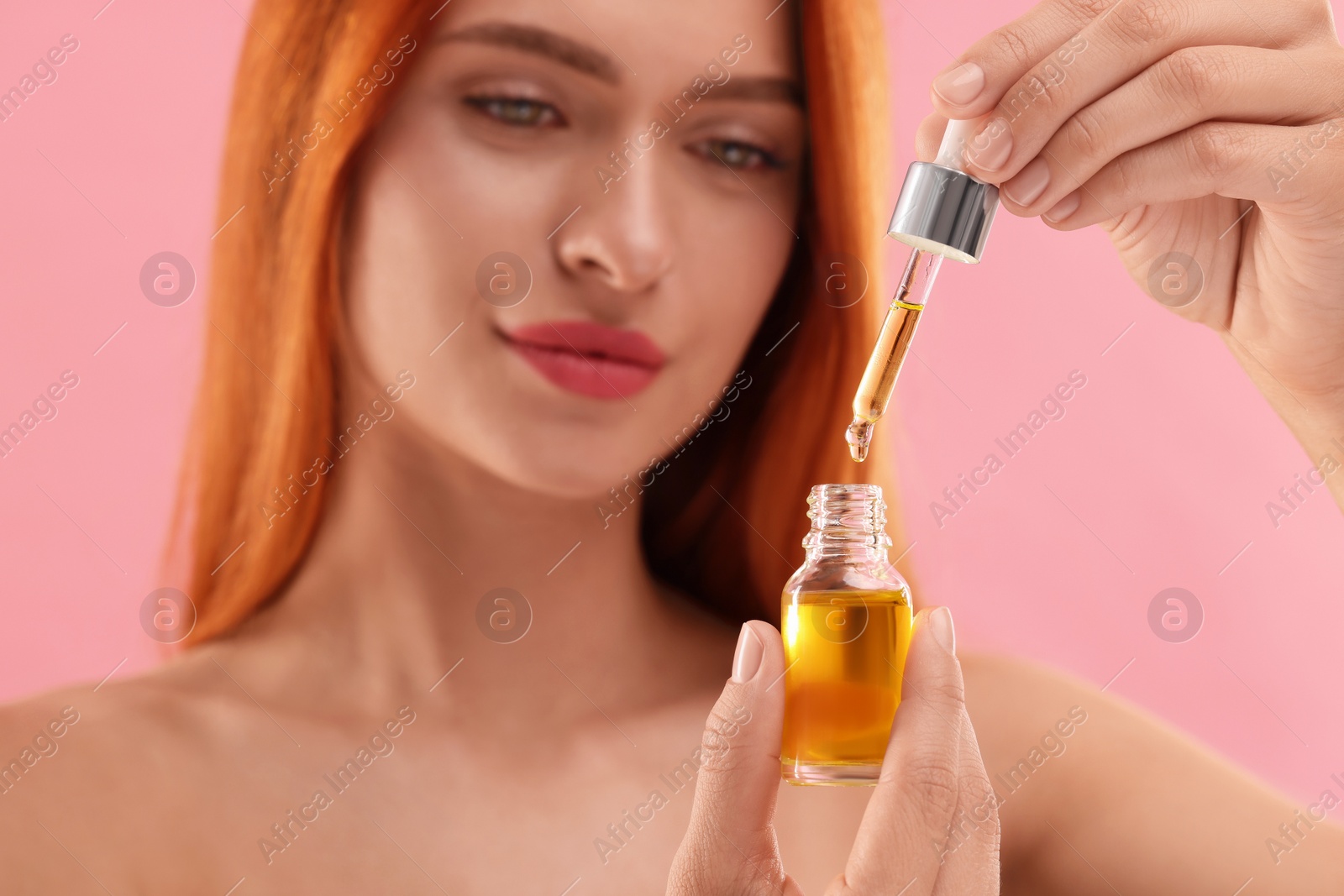 Photo of Beautiful young woman with bottle of serum on pink background, selective focus