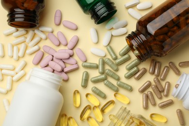 Many different vitamin pills and bottles on beige background, flat lay