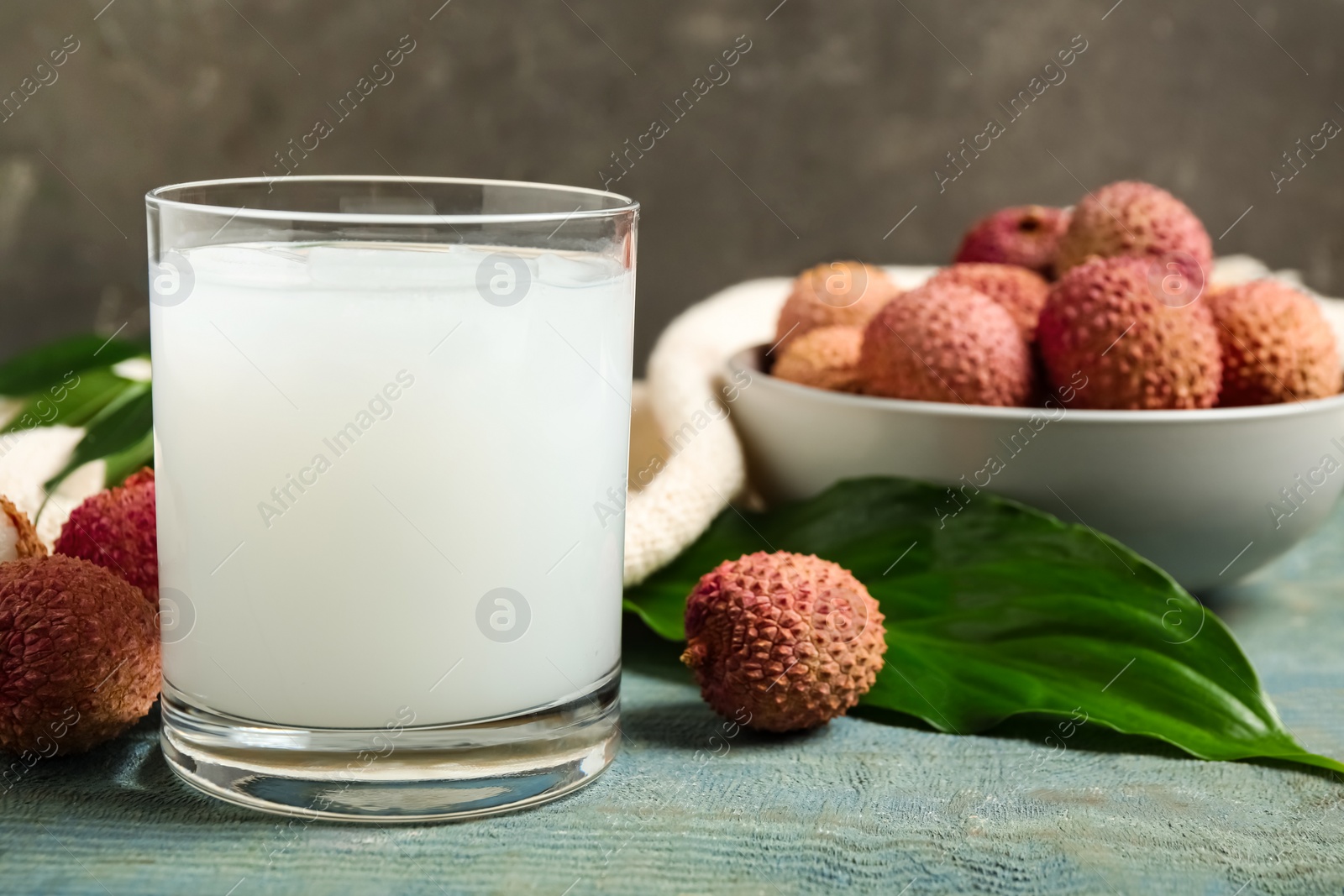Photo of Fresh lychee juice and fruits on blue wooden table