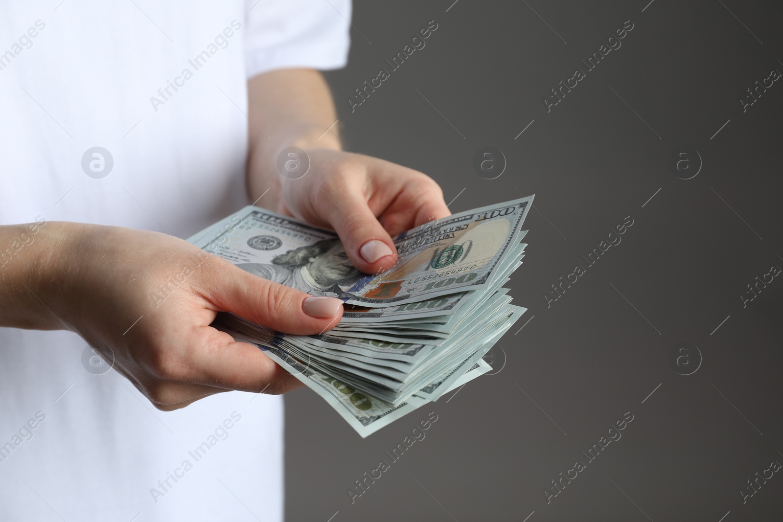 Photo of Money exchange. Woman counting dollar banknotes on grey background, closeup. Space for text