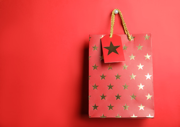 Photo of Shopping paper bag with star pattern on red background, space for text