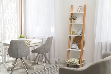 Stylish living room interior with wooden ladder near white wall