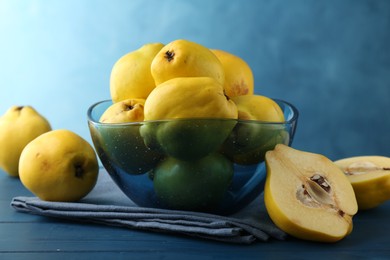 Photo of Tasty ripe quinces in bowl on blue wooden table, closeup